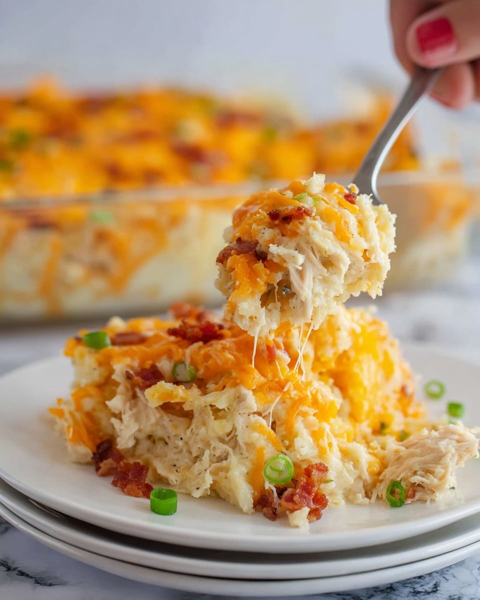 The dish on a white plate shows a thick, creamy baked casserole with two main layers: the bottom layer is light and creamy with a mix of white and pale yellow colors, showing strands of tender noodles and bits of cooked white meat, while the top layer is a bright orange shredded cheese crust sprinkled with small pieces of crispy bacon and green herbs. A fork lifts up a portion, showing the gooey, cheesy texture mixed with the soft noodles and meat, all resting on a smooth white marbled surface. Photo taken with an iphone --ar 4:5 --v 7