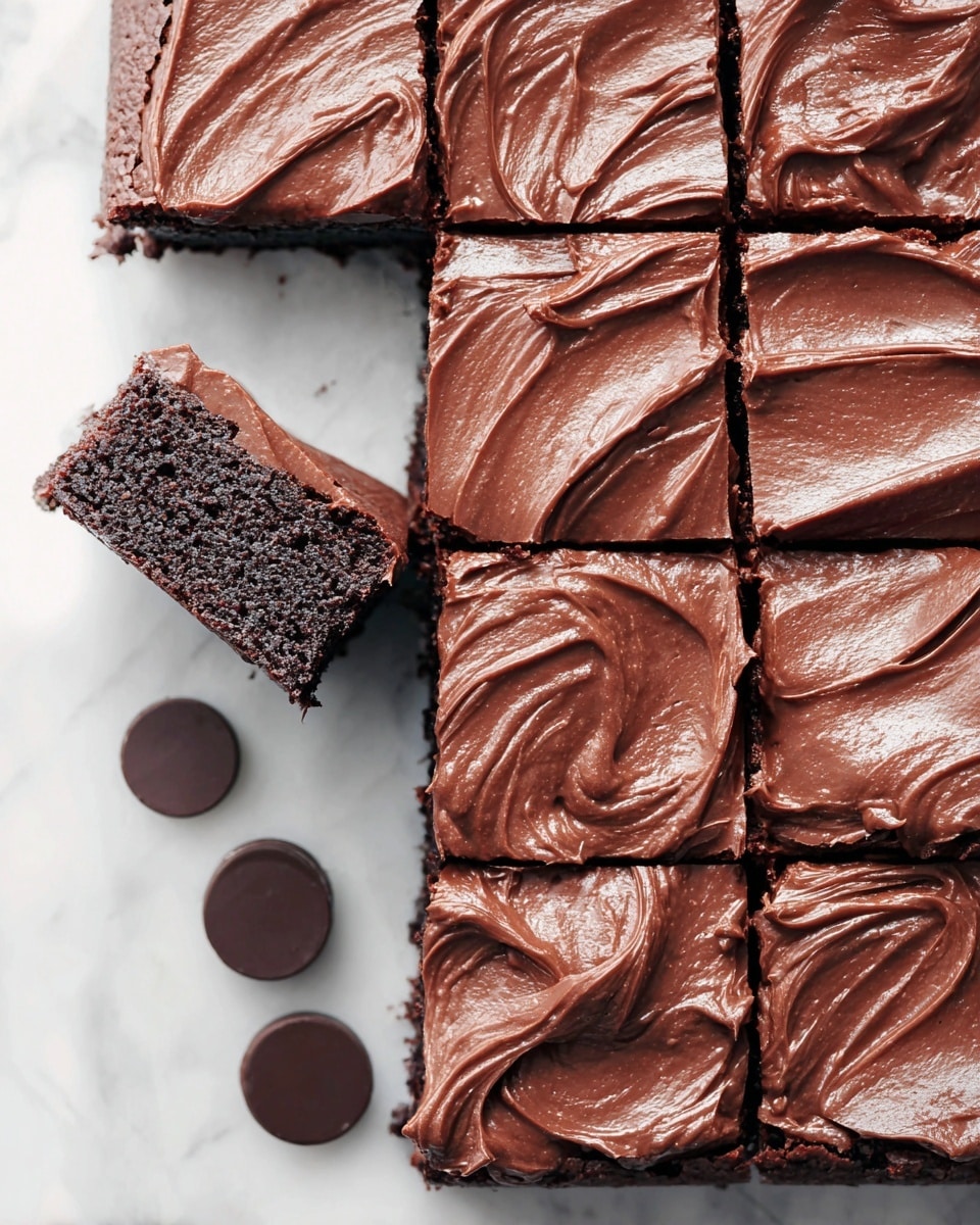 A close-up view of a grid of 12 square chocolate brownies on a white marbled surface, with each brownie topped by a thick, creamy layer of smooth chocolate frosting that has soft swirls and a slightly glossy texture; one brownie is pulled out slightly from the bottom left corner, showing the rich dark chocolate base beneath the frosting; near the bottom of the image are three round pieces of dark chocolate placed on the marble surface. photo taken with an iphone --ar 4:5 --v 7