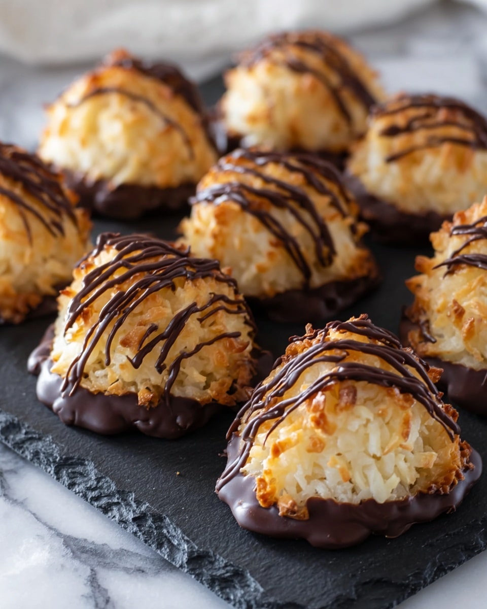 The image shows seven golden-brown coconut macaroons arranged on a round black slate plate. Each macaroon has a rough, toasted coconut texture on the top layer with a slightly pointed dome shape. The bottom half of the macaroons is dipped in dark chocolate, giving a smooth, glossy dark brown layer. Thin, uneven drizzles of dark chocolate are scattered over the top and sides of each macaroon, creating a fine contrast against the light toasted coconut. The plate is placed on a white marbled surface with a soft cloth in the background. photo taken with an iphone --ar 4:5 --v 7