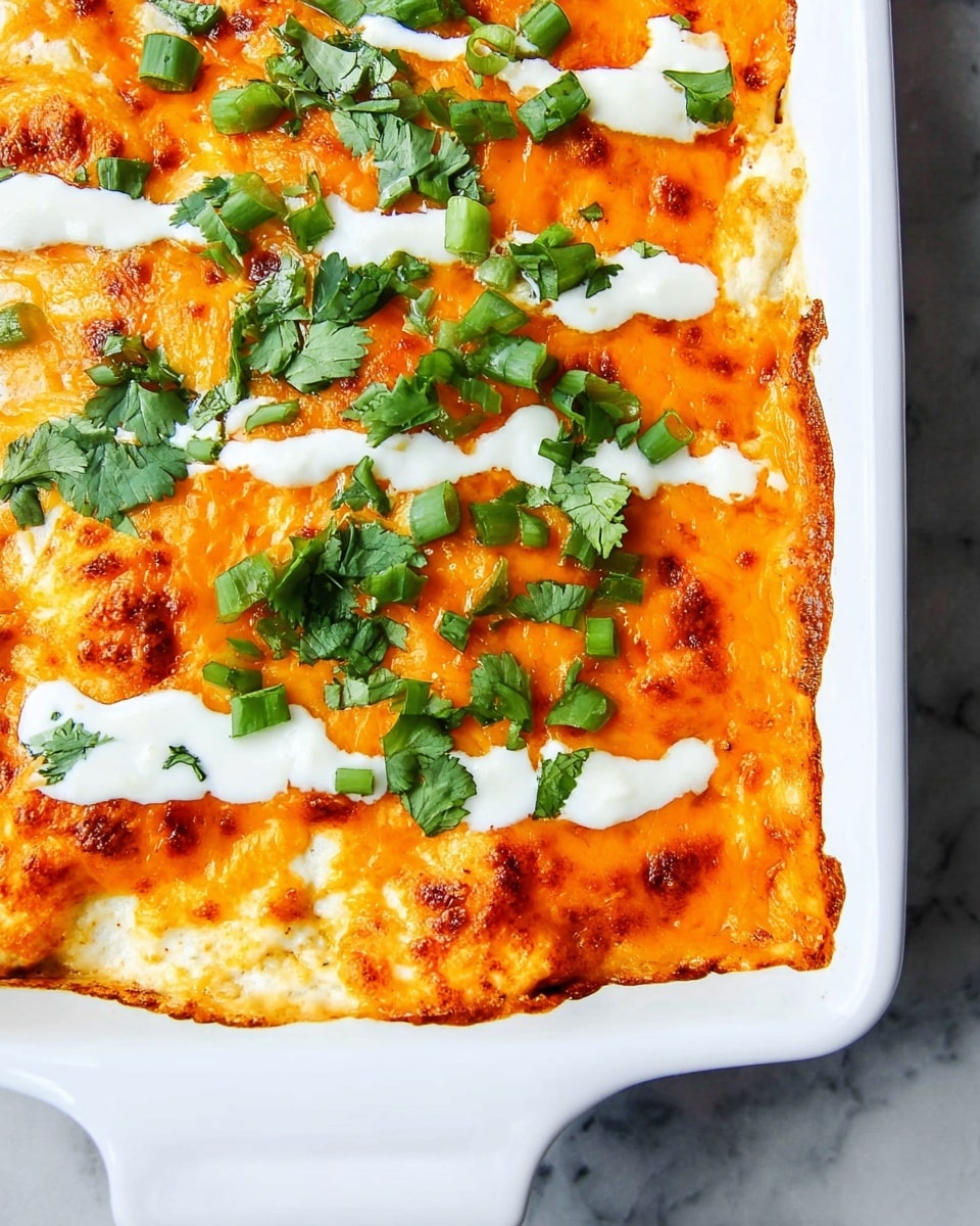 A white baking dish filled with a baked layer of creamy, melted bright orange cheese covering the top. White sauce is drizzled in thick lines across the dish, adding a smooth contrast. Green onion slices and fresh cilantro leaves are scattered on top, adding bright green color and fresh texture. The edges show slightly browned, melted cheese curling up against the sides of the dish. The surface beneath has a white marbled texture. photo taken with an iphone --ar 4:5 --v 7